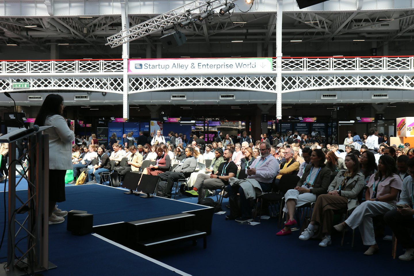 Woman speaking from a podium to an audience at a conference.